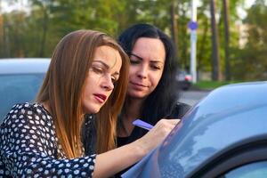 jung Frau mit ihr Freund Unterzeichnung ein dokumentieren auf das Kofferraum von ein Auto foto