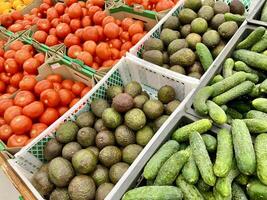 Grün Gurken, Avocados, rot Tomaten auf Landwirte Essen Markt Stall mit verschiedene organisch Gemüse. foto