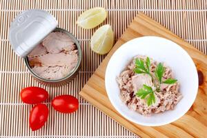 Dosen- Thunfisch im Keramik Schüssel auf hölzern Schneiden Tafel oben Aussicht foto