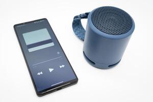 tragbar kabellos Blau Lautsprecher mit Smartphone isoliert auf Weiß Hintergrund. foto