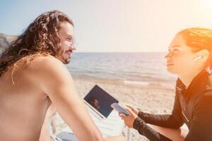 Mann Frau Laptop Meer. Arbeiten entfernt auf Strand. glücklich erfolgreich Paar, Freiberufler Arbeiten auf Meer Strand, erleichtert Stress von Arbeit zu wiederherstellen Leben Gleichgewicht. freiberuflich, Fernbedienung Arbeit auf Ferien foto