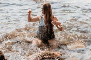 Frau Sommer- Reise Meer. glücklich Tourist genießen nehmen Bild draußen zum Erinnerungen. Frau Reisender posieren auf das Strand beim Meer umgeben durch vulkanisch Berge, Teilen Reise Abenteuer Reise foto