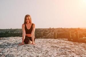 Fitness Frau. glücklich mittleren Alters Fitness Frau tun Dehnen und Pilates auf ein Felsen in der Nähe von Wald beim Sonnenuntergang. weiblich Fitness Yoga Routine. gesund Lebensstil mit Fokus auf Wohlbefinden und Entspannung. foto