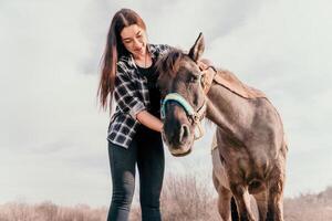 jung glücklich Frau mit ihr Pony Pferd im Abend Sonnenuntergang Licht. draussen Fotografie mit Mode Modell- Mädchen. Lebensstil Stimmung. Konzept von draussen Reiten, Sport und Erholung. foto