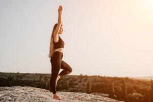 Fitness Frau. glücklich mittleren Alters Fitness Frau tun Dehnen und Pilates auf ein Felsen in der Nähe von Wald beim Sonnenuntergang. weiblich Fitness Yoga Routine. gesund Lebensstil mit Fokus auf Wohlbefinden und Entspannung. foto