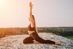 Fitness Frau. glücklich mittleren Alters Fitness Frau tun Dehnen und Pilates auf ein Felsen in der Nähe von Wald beim Sonnenuntergang. weiblich Fitness Yoga Routine. gesund Lebensstil mit Fokus auf Wohlbefinden und Entspannung. foto