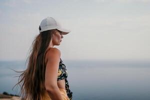 Frau Reise Meer. glücklich Tourist nehmen Bild draußen zum Erinnerungen. Frau Reisender sieht aus beim das Kante von das Cliff auf das Meer Bucht von Berge, Teilen Reise Abenteuer Reise foto