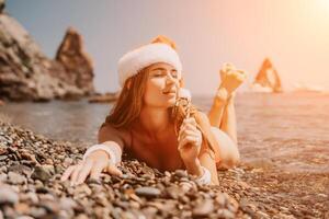 Frau Reise Meer. glücklich Tourist genießen nehmen Bild auf das Strand zum Erinnerungen. Frau Reisender im Santa Hut sieht aus beim Kamera auf das Meer Bucht, Teilen Reise Abenteuer Reise foto