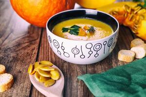 Sahne Kürbis Suppe mit frisch Kräuter und Cracker auf dunkel hölzern Hintergrund. gesund Lebensmittel. selektiv Fokus. foto