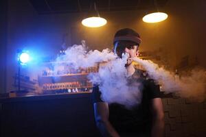 vaping Mann halten ein Mod. ein Wolke von Dampf beim das Dampfen Geschäft. foto