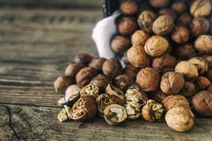 frisch Walnüsse verschütten aus von ein Korbweide Korb auf Herbst Hintergrund auf das alt hölzern Tisch, gesund Essen cocept, selektiv Fokus foto