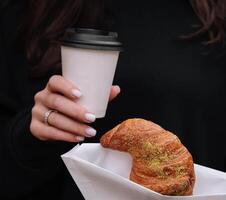 Mädchen Essen Croissant mit Pistazie Pulver und Trinken Kaffee auf Terrasse foto