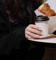 Mädchen Essen Croissant mit Pistazie Pulver und Trinken Kaffee auf Terrasse foto