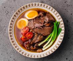 Bohnenkraut Rindfleisch Ramen Schüssel mit Ei und Gemüse foto