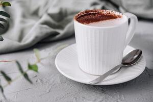 frisch Cappuccino im ein Weiß Tasse auf ein grau Oberfläche foto