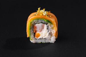 exquisit Gold Blatt Sushi rollen auf ein schwarz Hintergrund foto