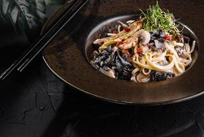 exquisit asiatisch Nudel Gericht auf elegant dunkel Teller foto