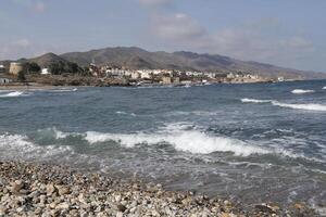 Bucht von Villaricos, Rau Meer, Strand, Dorf und Berge beim das Hintergrund foto