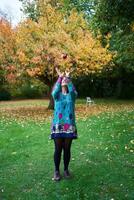 ein Mädchen im ein Kleid mit Luftballons ist spielen im das Herbst Garten foto