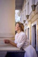 elegant Mitte Alter Frau im Weiß Jahrgang Kleid in der Nähe von Theater mit Antiquität Kolonnaden foto