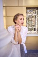 elegant Mitte Alter Frau im Weiß Jahrgang Kleid in der Nähe von Theater mit Antiquität Kolonnaden foto