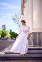 elegant Mitte Alter Frau im Weiß Jahrgang Kleid in der Nähe von Theater mit Antiquität Kolonnaden foto