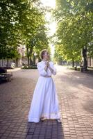 schick Mitte Alter Frau im ein Weiß Jahrgang Kleid im ein sonnendurchflutet Gasse foto