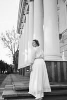 elegant Mitte Alter Frau im Weiß Jahrgang Kleid in der Nähe von Theater mit Antiquität Kolonnaden foto