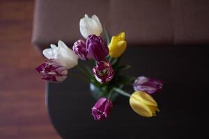 Strauß von mehrfarbig Tulpen im ein transparent Krug im das Innere foto