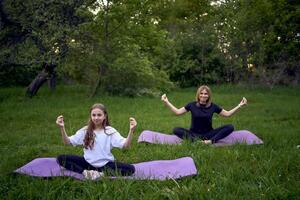 ein Frau und Mädchen tun Yoga und meditieren im Natur foto