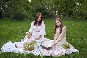 Schwestern von anders Alter Umarmung jeder andere zärtlich auf ein Picknick im das Garten foto