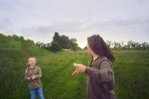 zwei wenig Schwestern und Mutter Lauf und starten ein Drachen im ein Feld foto