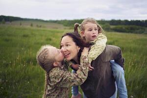 ein Mutter Rollen ihr Töchter auf ihr zurück, spielen Pferd, Küsse und Umarmungen foto