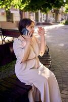 ein Plus Größe Frau im Pfirsich Flaum Kleid reden auf Telefon im Morgen Stadt foto