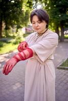 Plus Größe Frau im Pfirsich Flaum Kleid und rot durchscheinend Handschuhe Tanzen im das Morgen Stadt Straßen foto