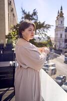 Plus Größe Frau im Pfirsich Flaum Kleid auf Terrasse mit Blick auf Kirche foto