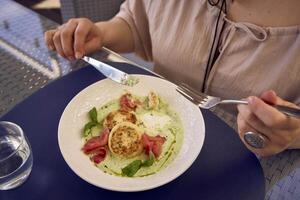 Mittel Größe Frau im Pfirsich Flaum Kleid Essen Hütte Käse Pfannkuchen mit Lachs und Spinat im modern Restaurant foto