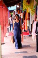 Dame im Blau Sommer- Kleid posieren draussen mit Einkaufen Taschen foto