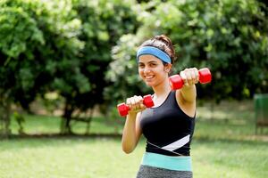 sexy sportlich Frau posieren mit Hanteln im Vorderseite von Kamera foto