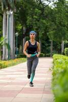 Frau Jogger im Fitnessstudio Outfit Laufen im das Park foto