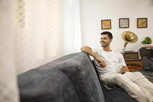 glücklich Kerl Sitzung auf das Sofa Denken Über Zukunft foto