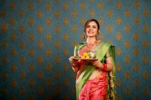 lächelnd ziemlich Dame halten Puja Thali im Hand während Karwa chauth Festival foto