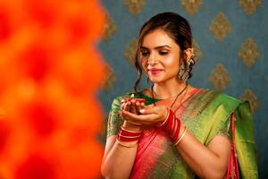 attraktiv reifen Dame im Saree halten Diya während Diwali Festival foto