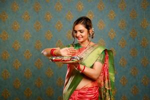 ein heiß jung Dame halten Teller von Diya im ihr Hand während Festival foto