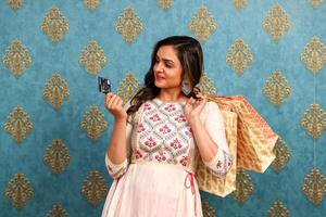 ein schön indisch Kleid Frau halten Lastschrift Karte und Einkaufen Taschen im Hand foto