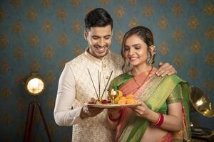 Lager Foto von ein Diwali Feier-Themen am meisten geliebt Paar halten ein pooja Teller im ihr Hände während gekleidet traditionell