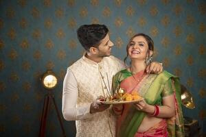 ein entspannt Paar im traditionell Outfit halten Puja Teller und Blick beim jeder andere foto