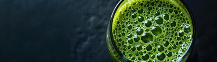 Nahansicht von ein Glas von Grün Saft mit Luftblasen auf ein schwarz Hintergrund foto