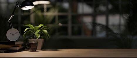 ein Büro Schreibtisch im ein modern, dunkel Büro beim Nacht beleuchtet durch ein dim Licht von ein Tabelle Lampe. foto