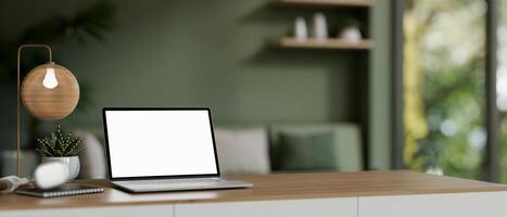 ein Zuhause Büro Arbeitsplatz mit ein Laptop Attrappe, Lehrmodell, Simulation auf ein Schreibtisch im ein modern Leben Zimmer mit Grün Farbe. foto